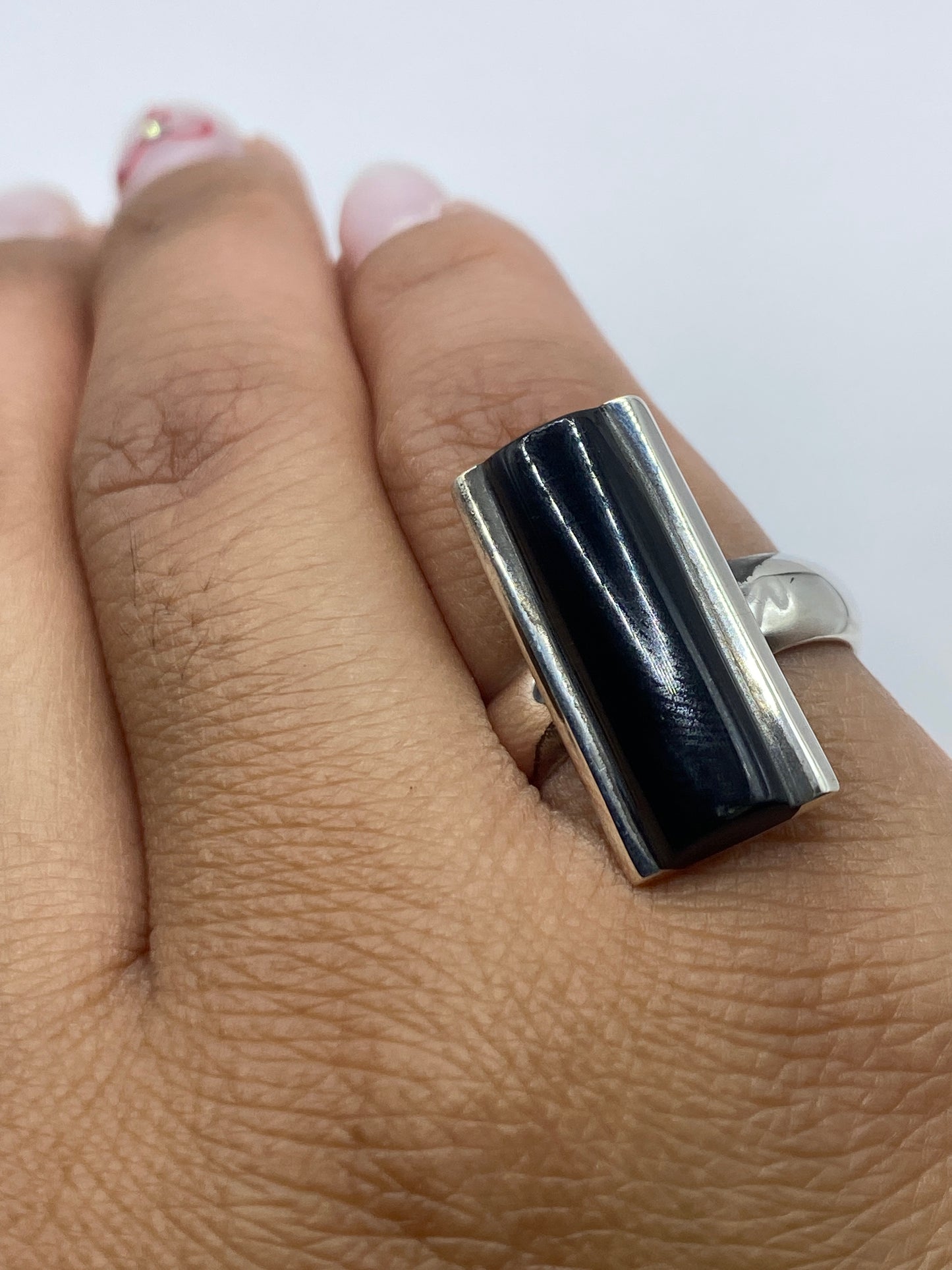 Anillo de ónix y plata en el dedo, mostrando el acabado pulido y la profundidad de la piedra