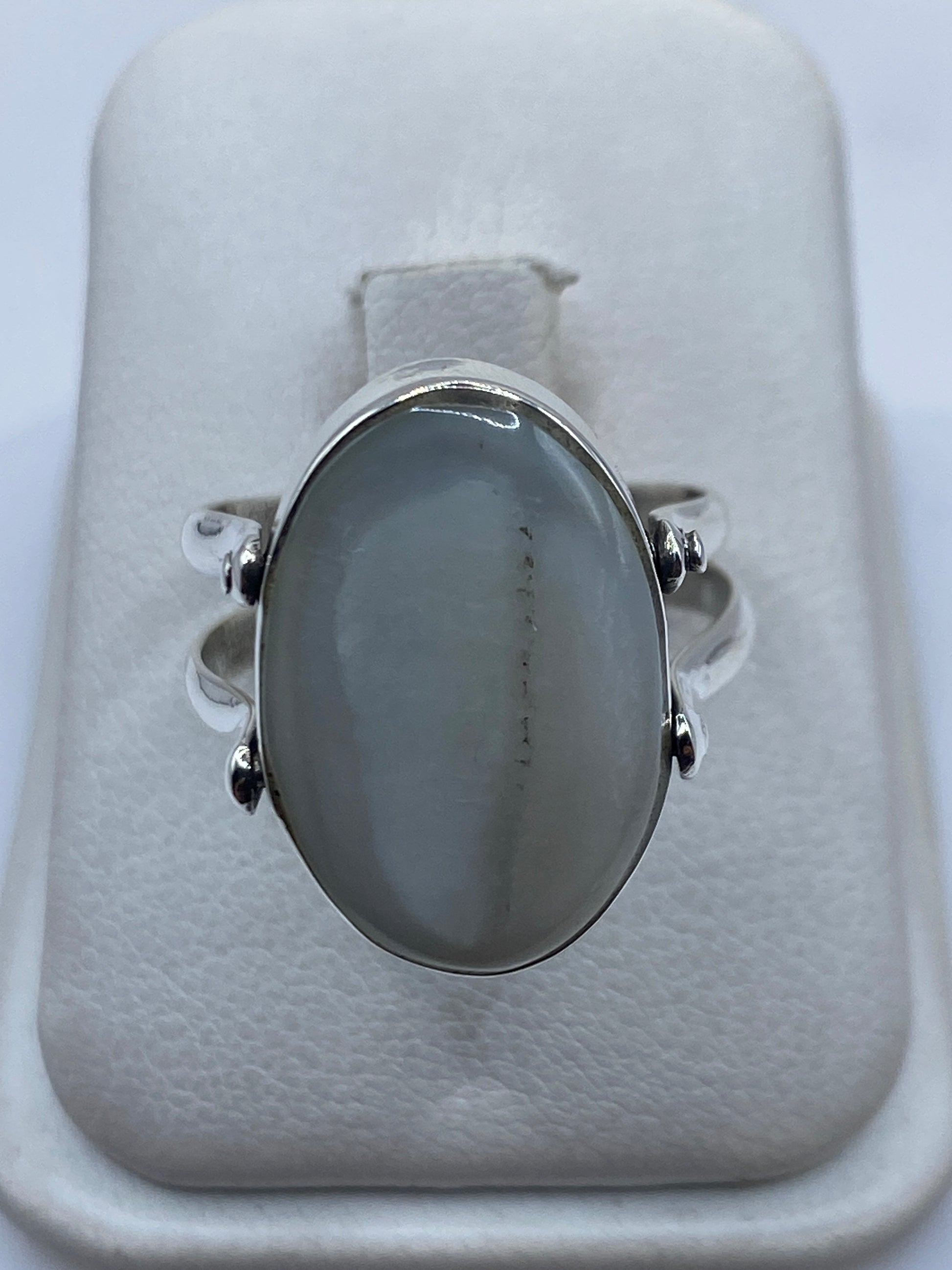 Anillo de plata con perla blanca engastada en la mano de una mujer