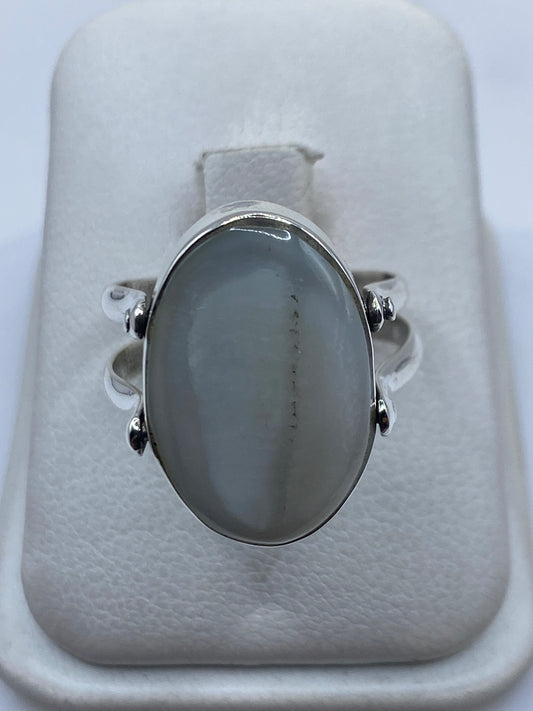 Anillo de plata con perla blanca engastada en la mano de una mujer
