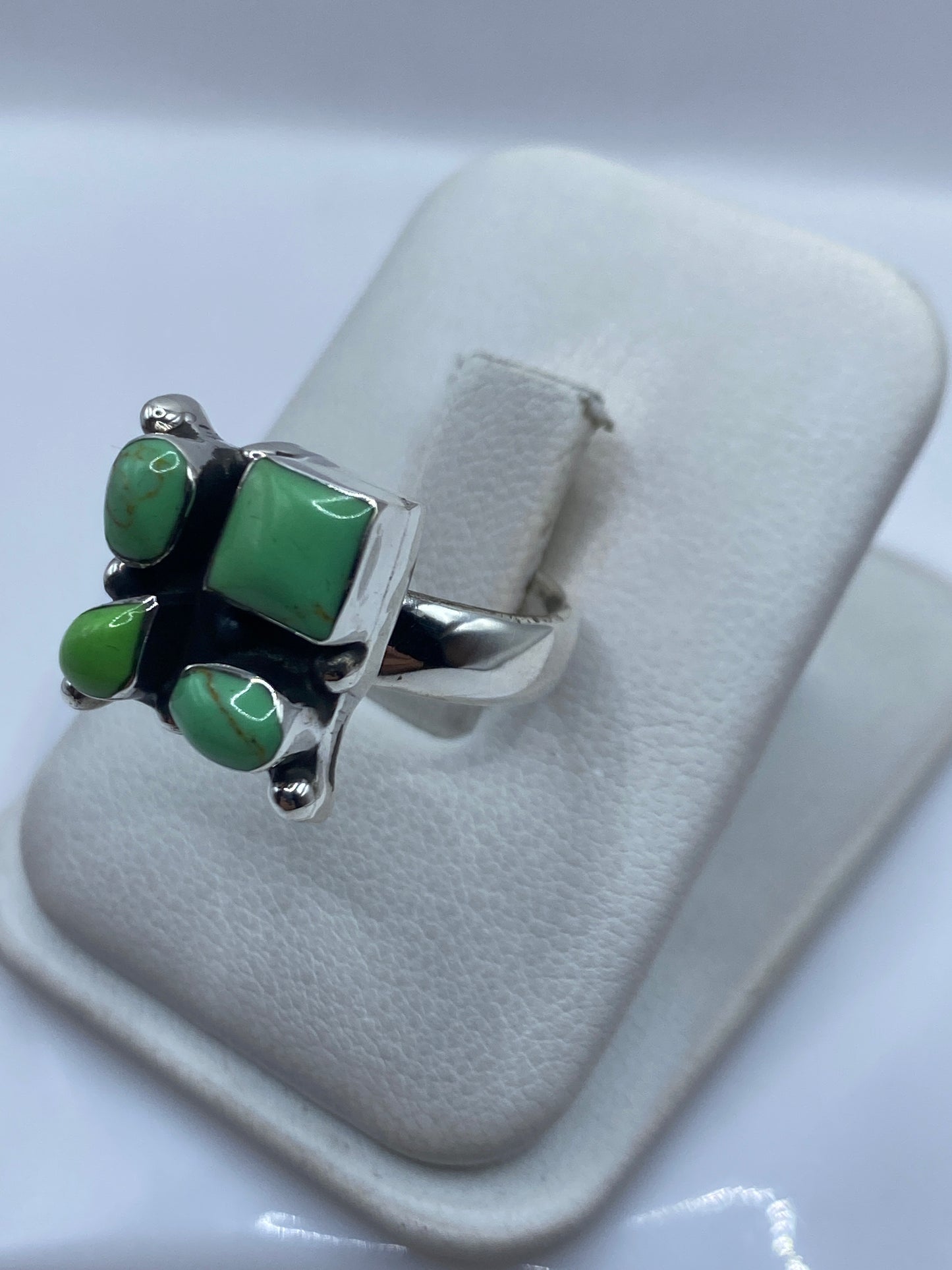 Vista frontal del anillo con piedras verdes y detalles de engaste a mano