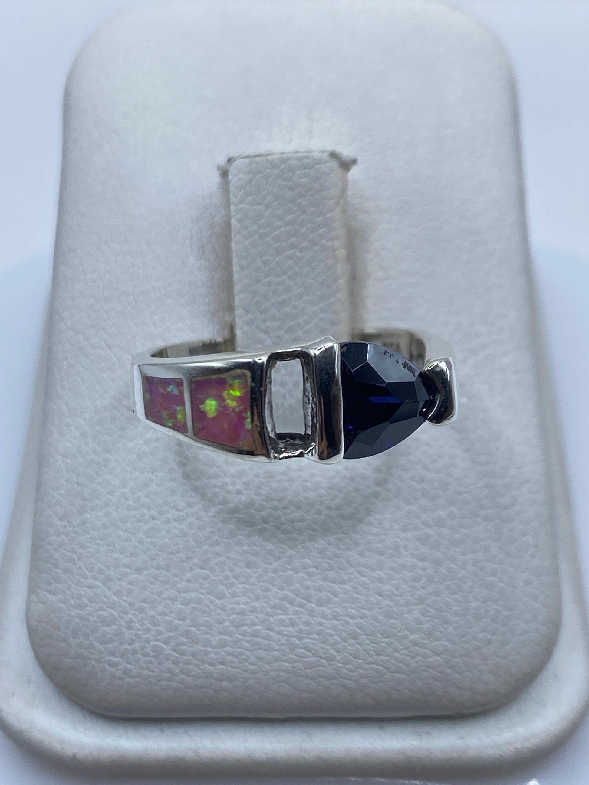 Anillo de plata con ópalo de fuego rosa en mano de mujer, mostrando el brillo vibrante de la piedra