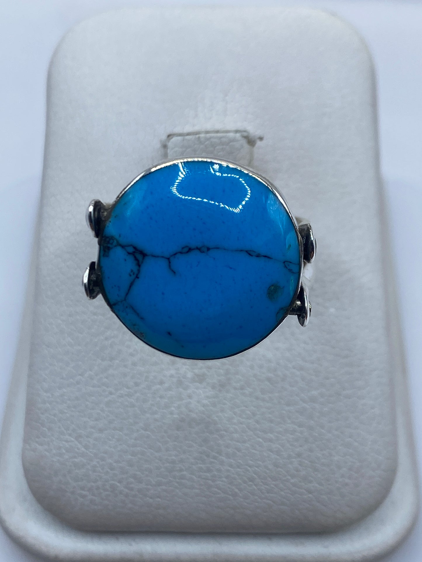 Anillo de plata con turquesa azul cielo y diseño prehispánico azteca en la mano de una mujer