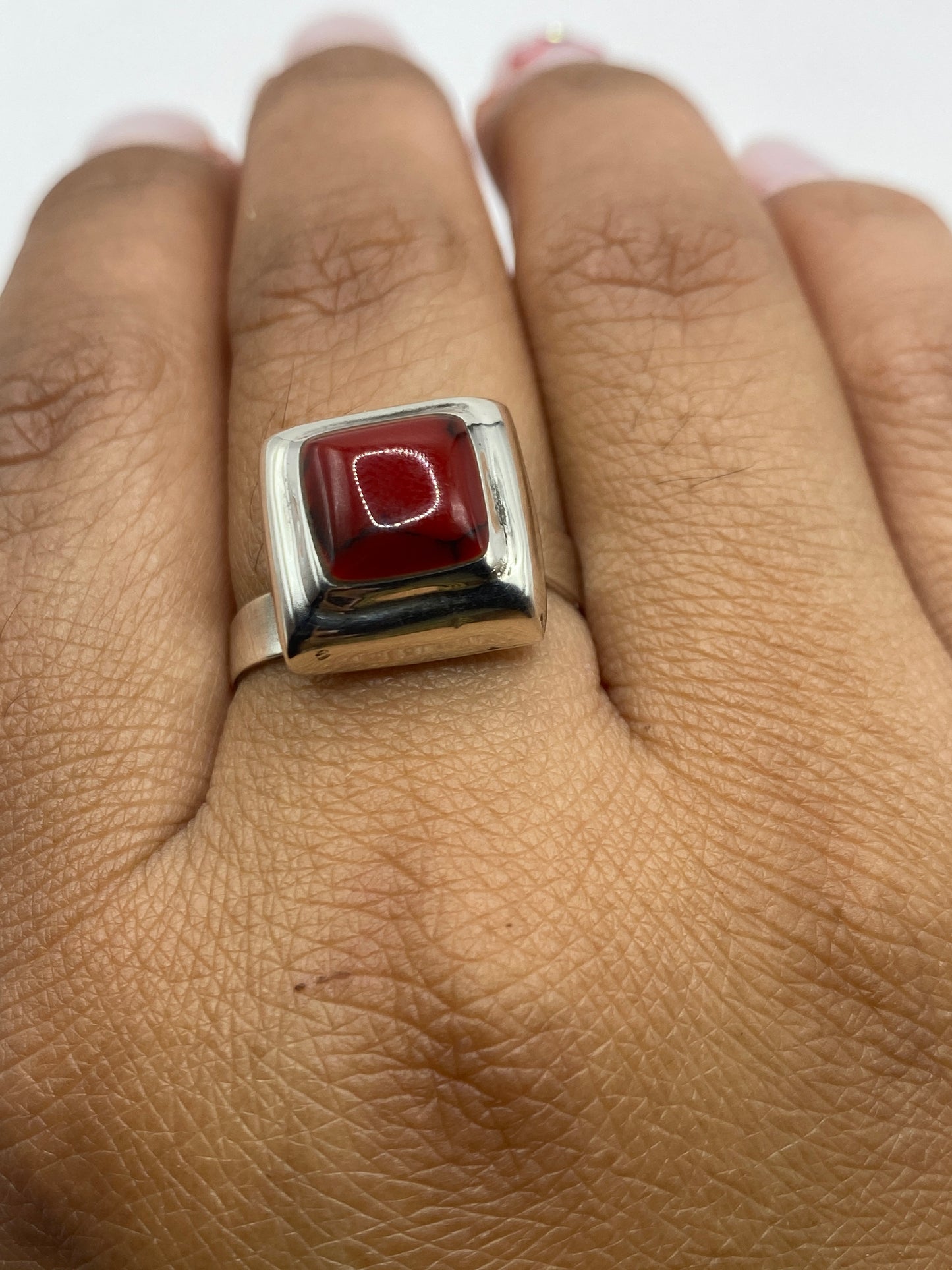 Anillo puesto en dedo mostrando el color rojo intenso del coral en contraste con la plata