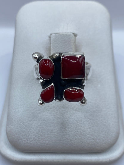 Anillo de plata .925 con cuatro cabujones de coral rojo engastado, diseño geométrico en mano de mujer