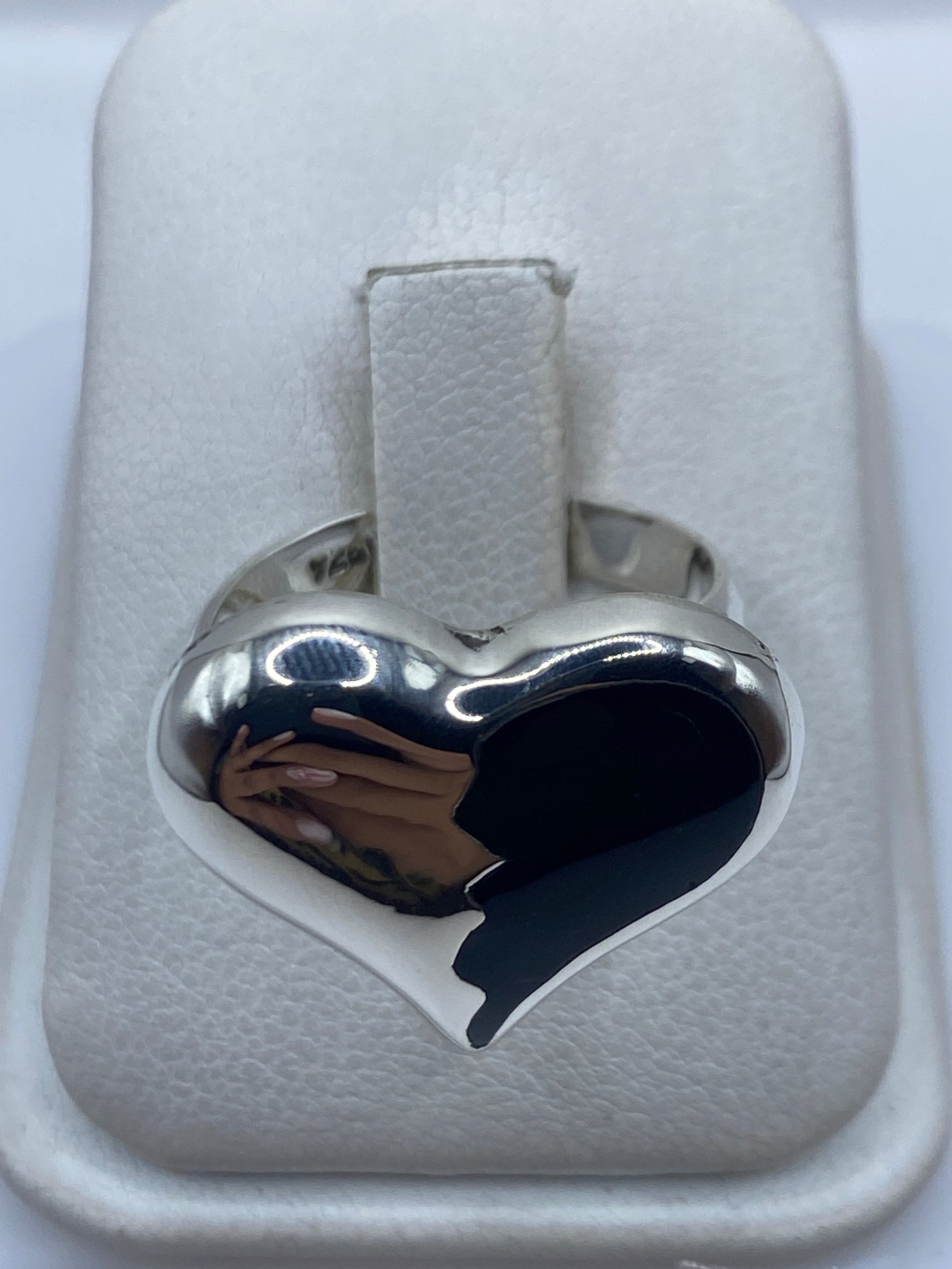 Anillo de plata ajustable con ónix negro en forma de corazón, visto de frente sobre estuche blanco