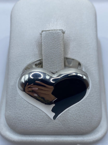 Anillo de plata ajustable con ónix negro en forma de corazón, visto de frente sobre estuche blanco