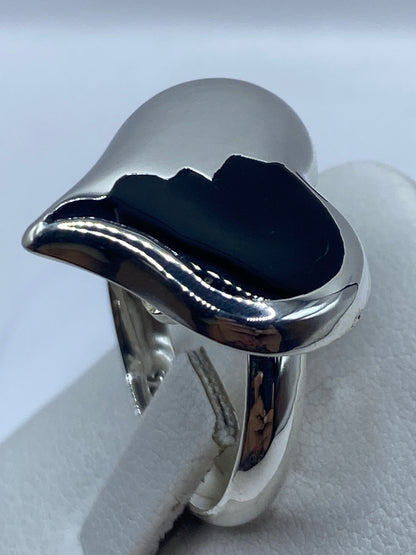 Anillo ajustable de ónix negro puesto en la mano de una mujer, mostrando el pulido espejo de la plata