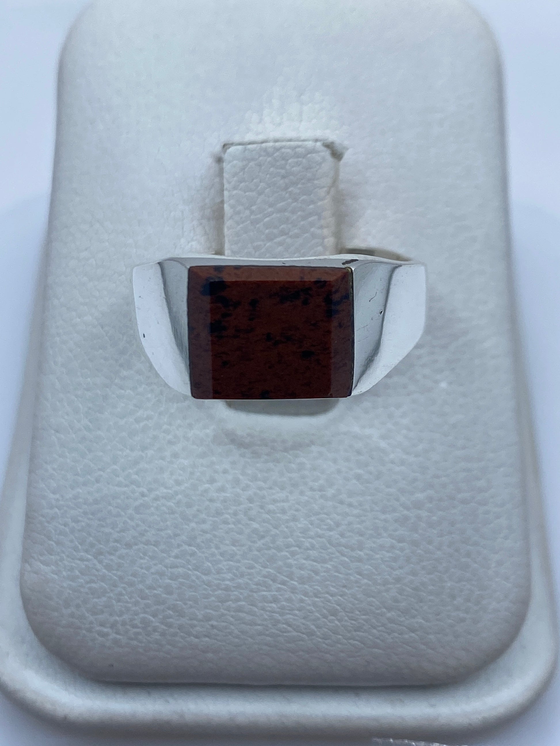 Anillo de plata .925 con piedra café engastada en mano, sobre fondo blanco