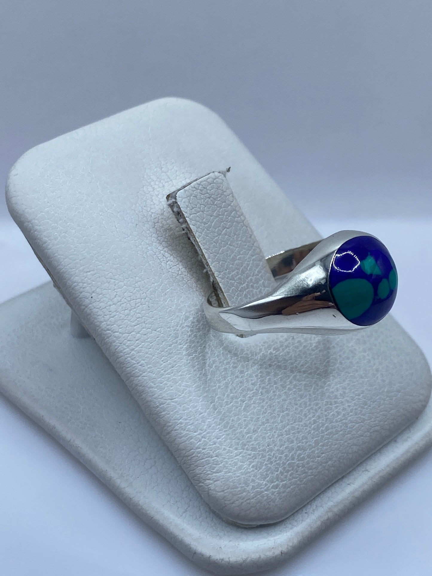 Anillo unisex de plata con piedra azul en la mano, vista lateral