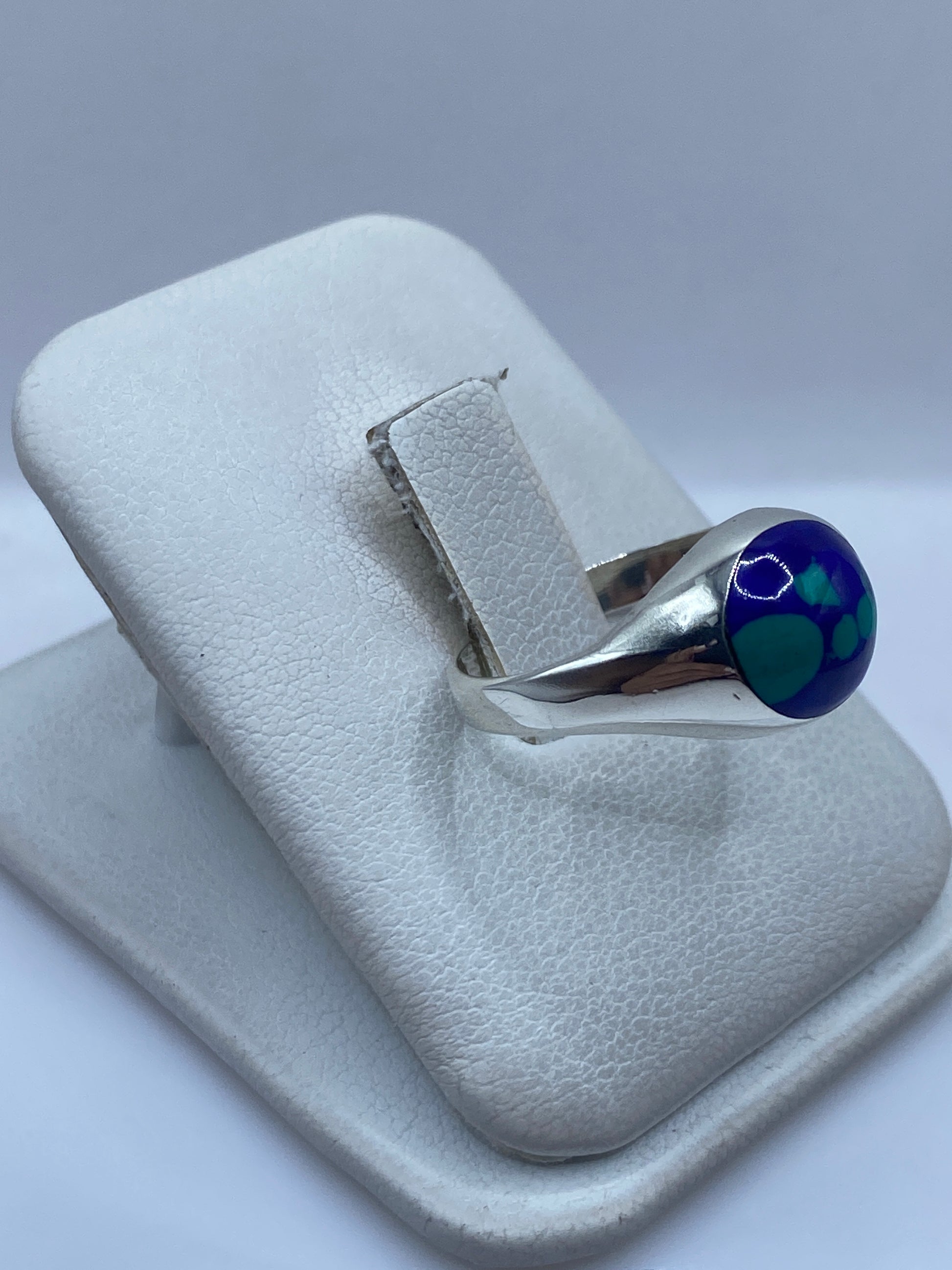 Anillo unisex de plata con piedra azul en la mano, vista lateral