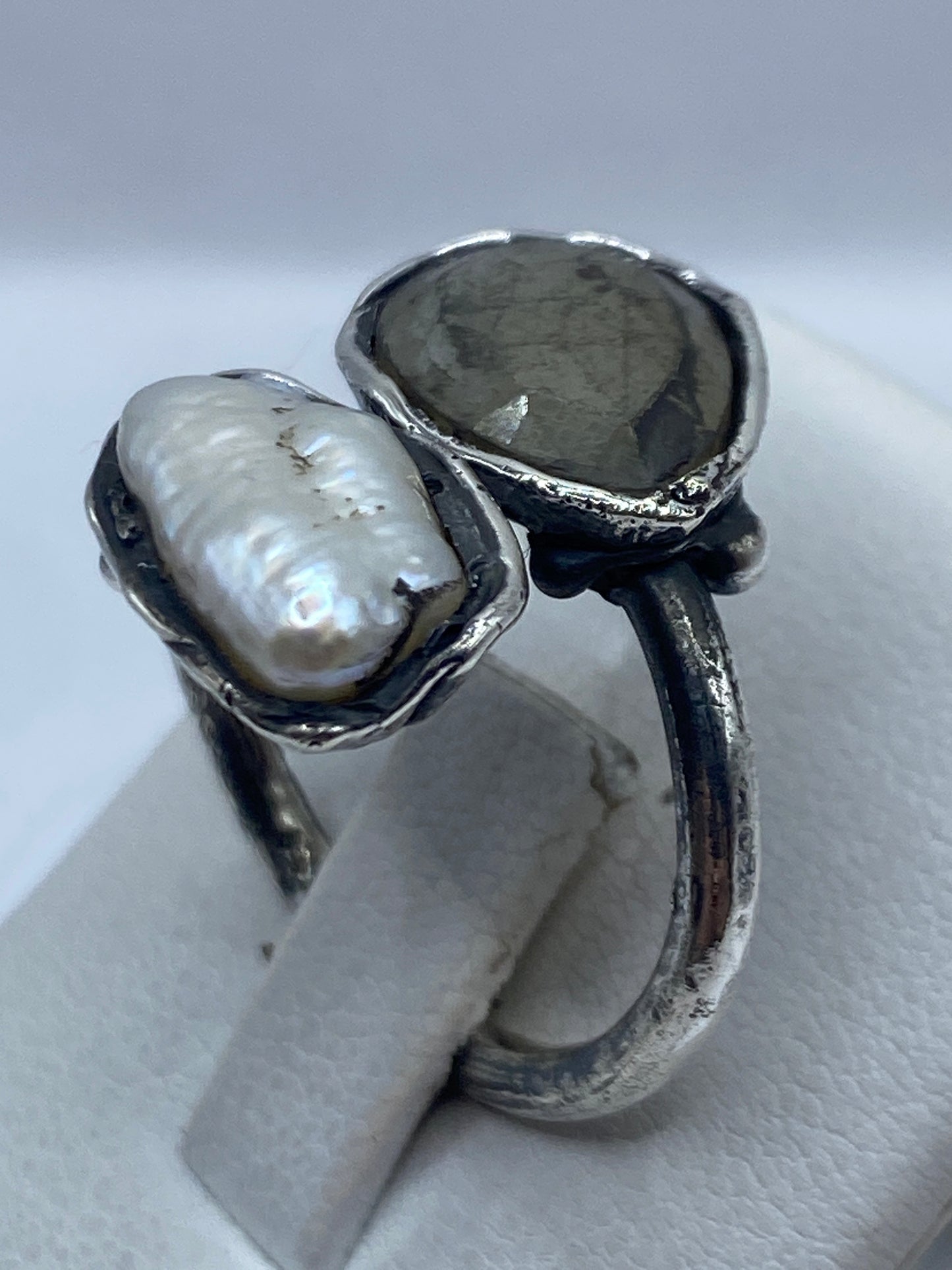 Anillo de plata con perla en la mano de una mujer, mostrando el engaste artesanal