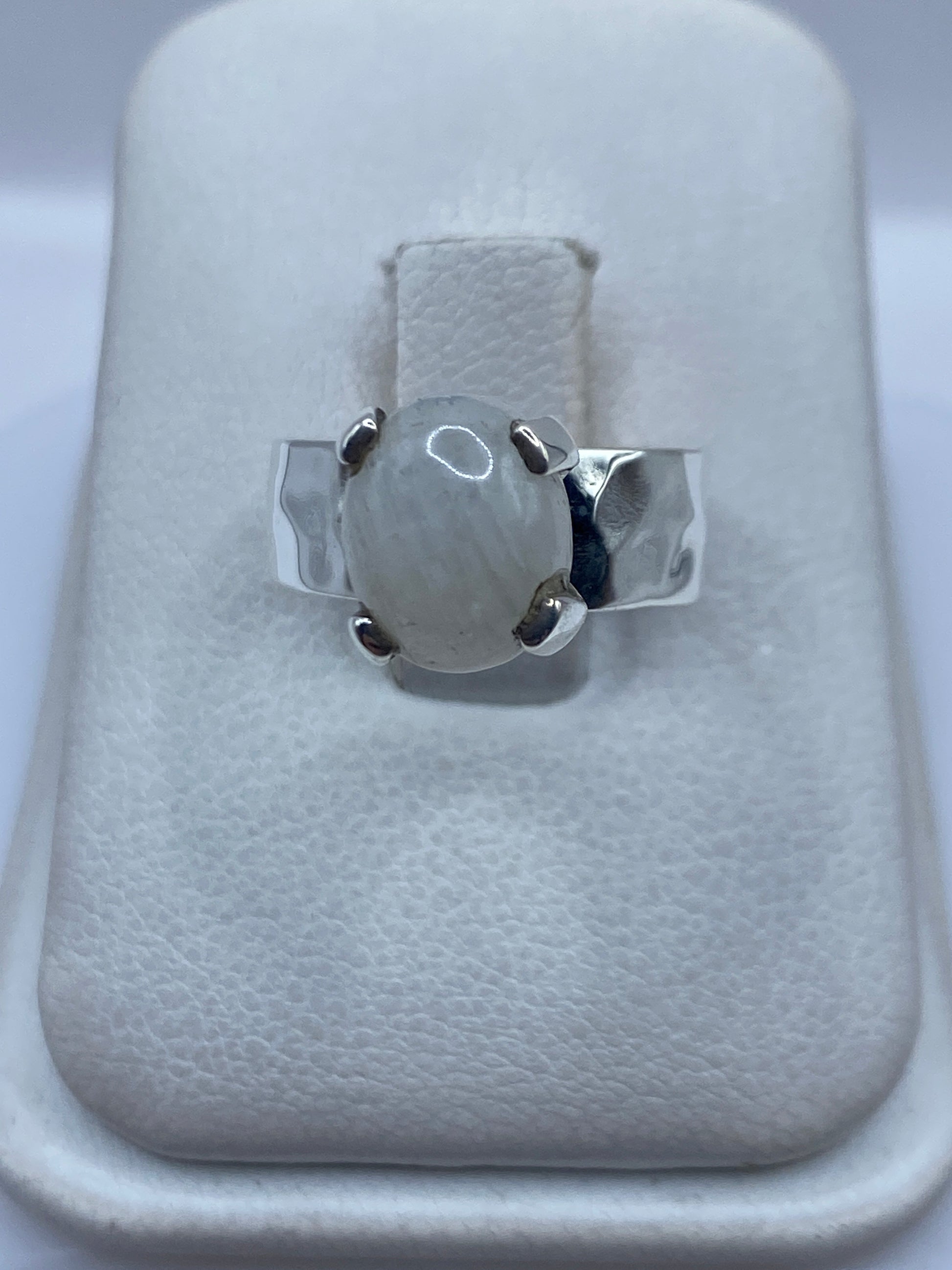 Anillo de plata .925 con piedra blanca engastada, visto de frente sobre estuche blanco