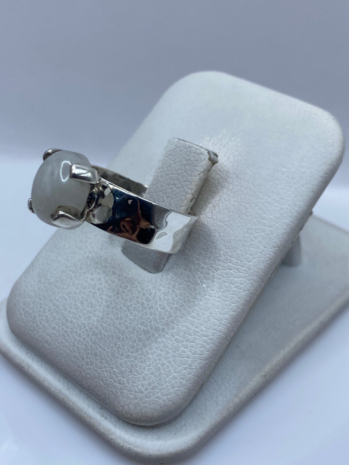 Anillo de plata minimalista con piedra blanca, vista lateral mostrando el perfil del montaje