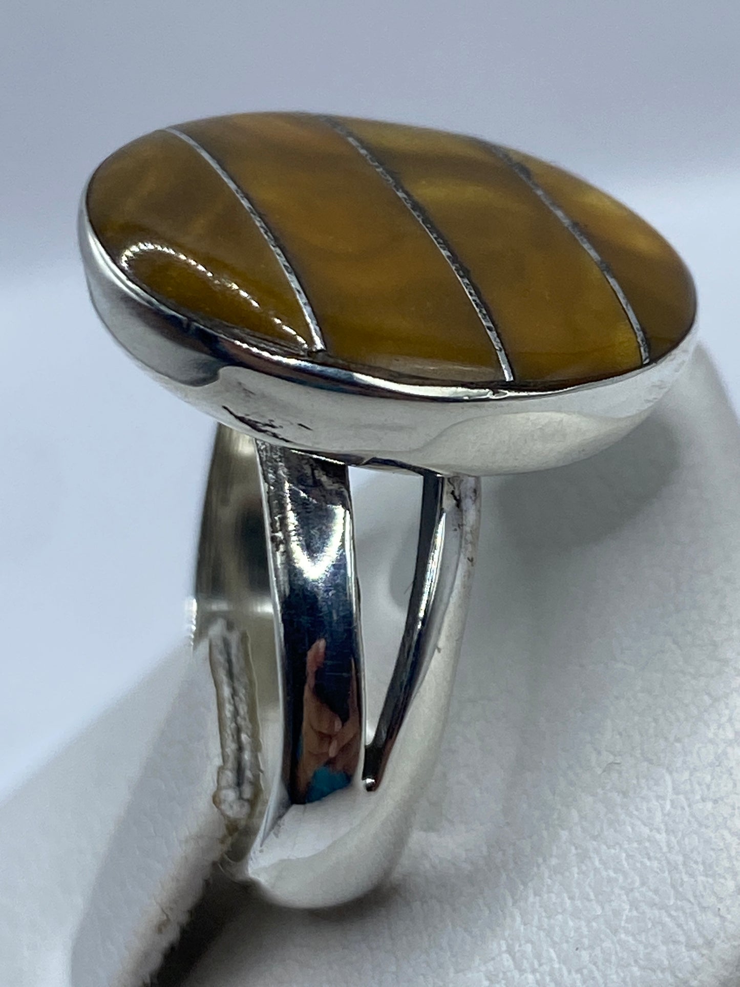 Anillo en dedo de mujer, piedra café brillante sobre plata pulida