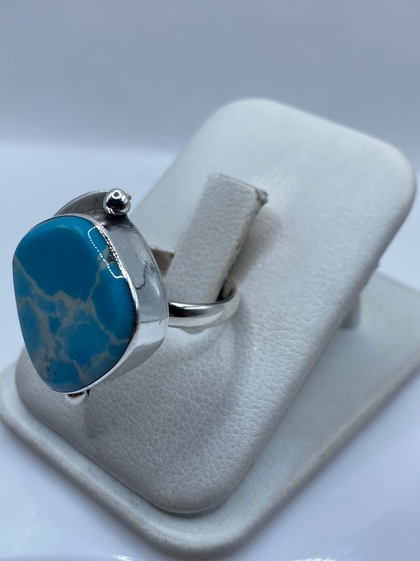 Anillo en dedo mostrando la talla ajustable y el brillo de la piedra azul