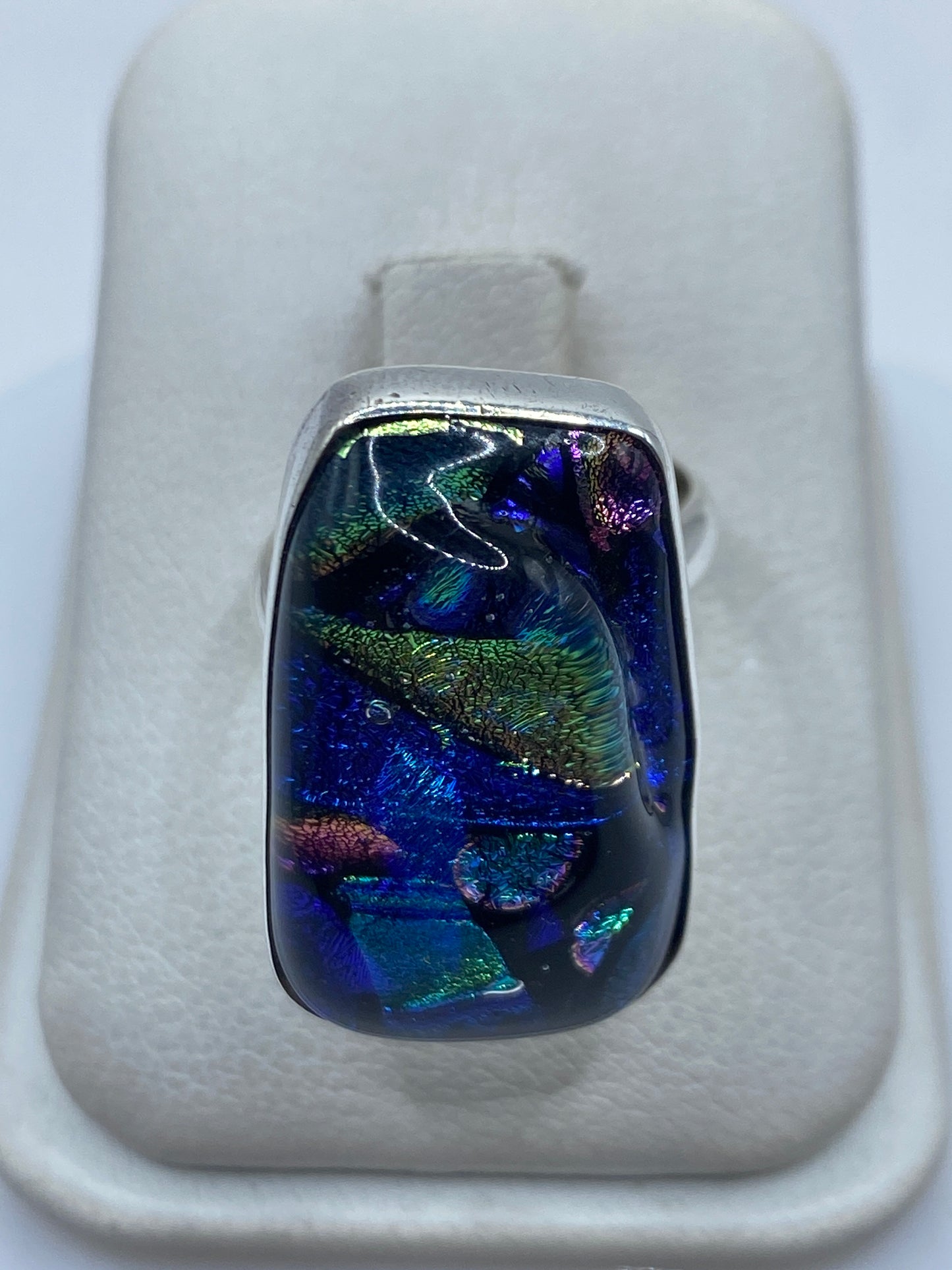 Anillo de plata ajustable con piedra multicolor azul, verde, dorado y violeta en mano de mujer