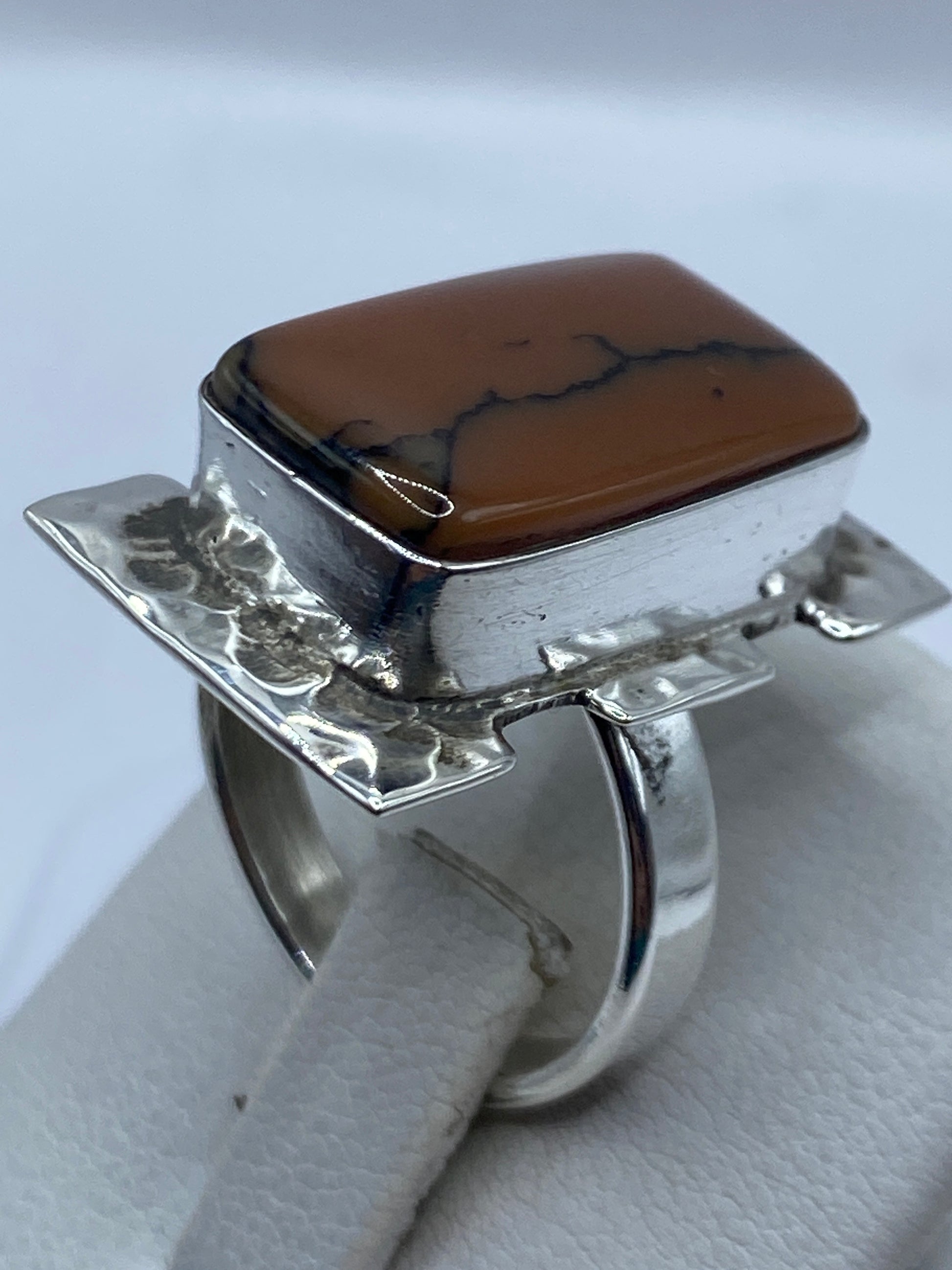 Detalle del engaste a mano y la piedra café en anillo de plata pulida