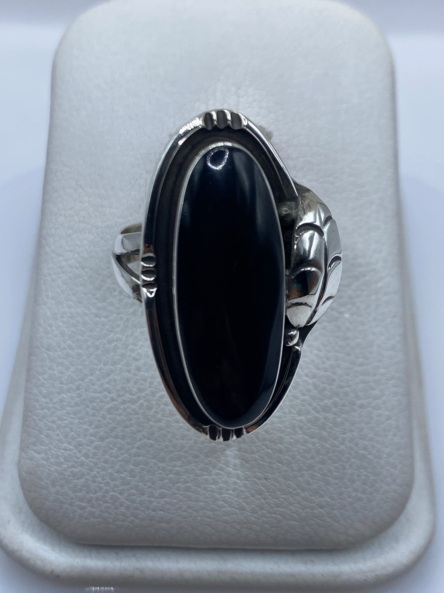 Anillo de plata con ónix negro y manos escultóricas a los lados, vista frontal