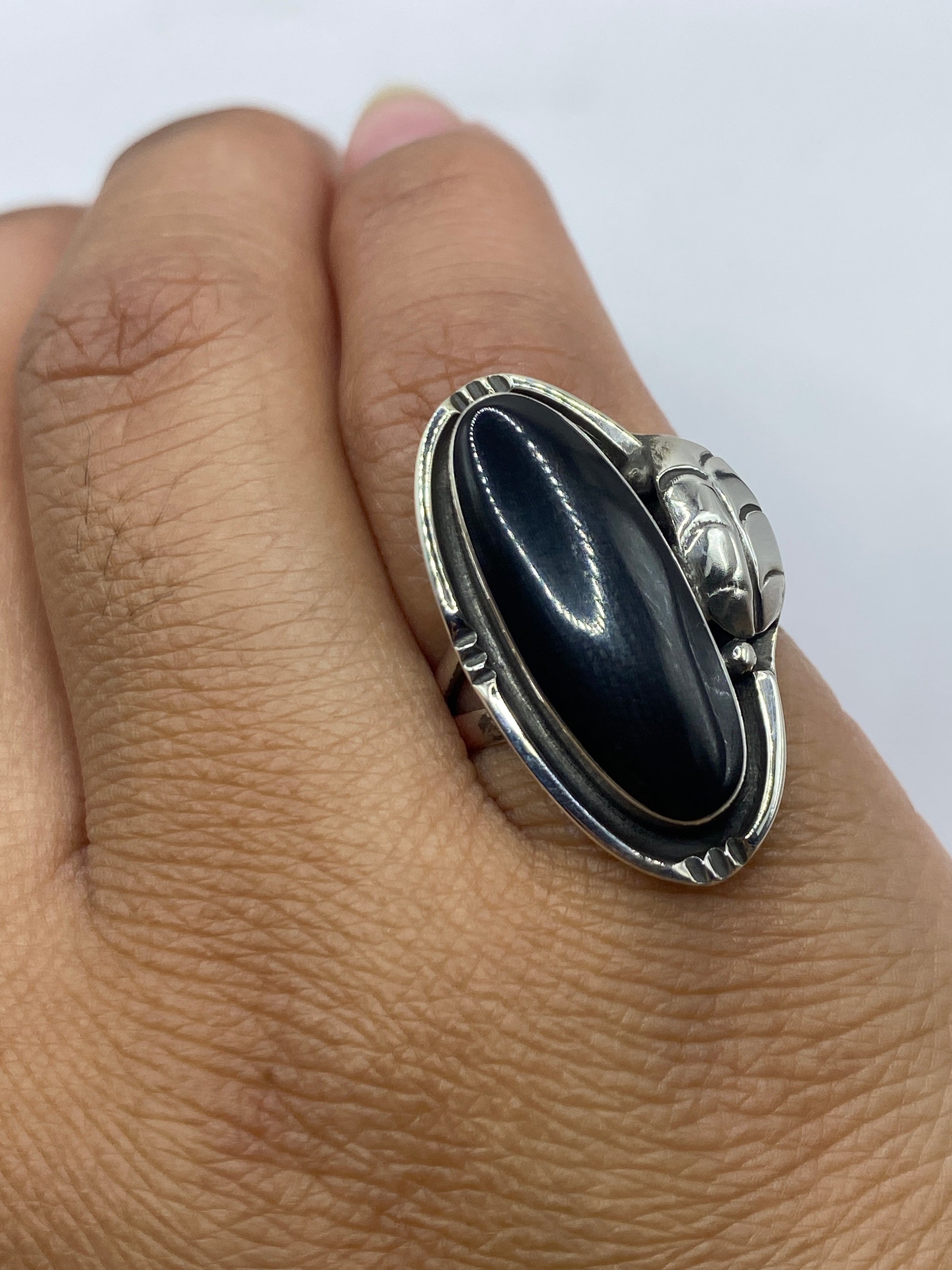 Anillo puesto en dedo, ónix negro brillante destacando contra la piel