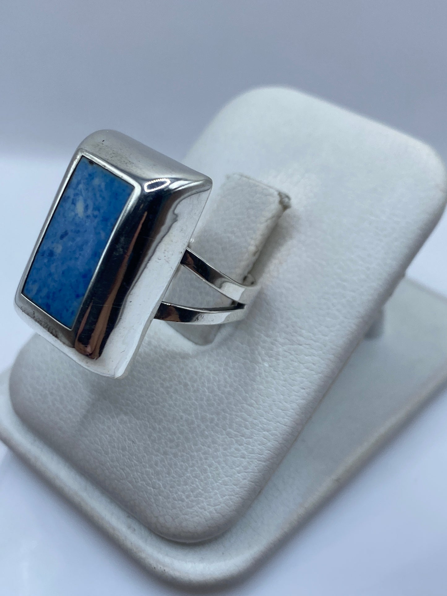 Anillo azul en la mano mostrando el engaste de piedra y el pulido de la plata