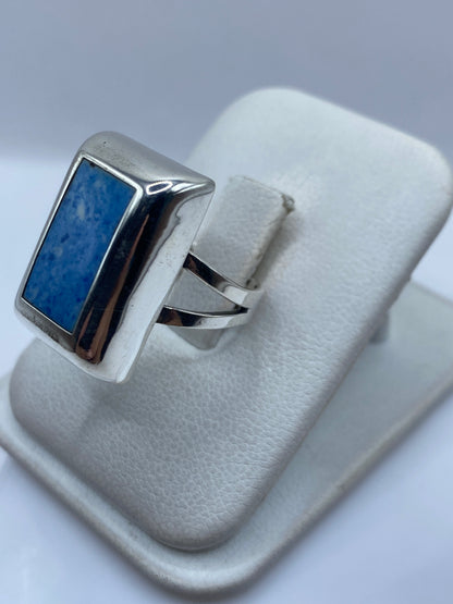 Anillo azul en la mano mostrando el engaste de piedra y el pulido de la plata