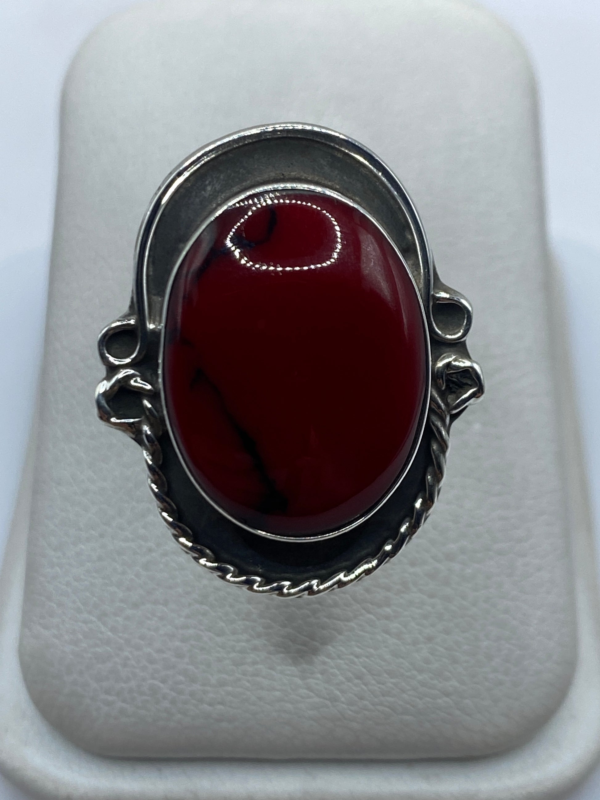 Anillo de plata ajustable con coral rojo vivo en mano de mujer