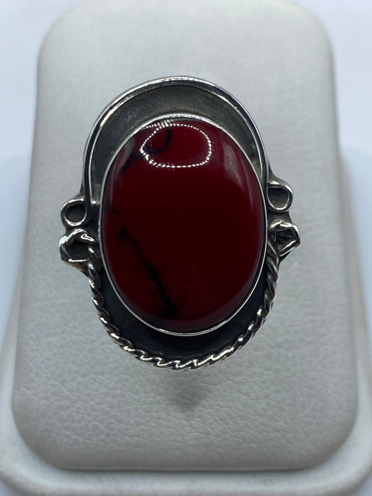 Anillo de plata ajustable con coral rojo vivo en mano de mujer