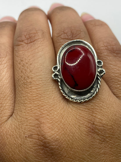 Anillo sobre fondo gris mostrando el brillo del coral y el Quinto .925