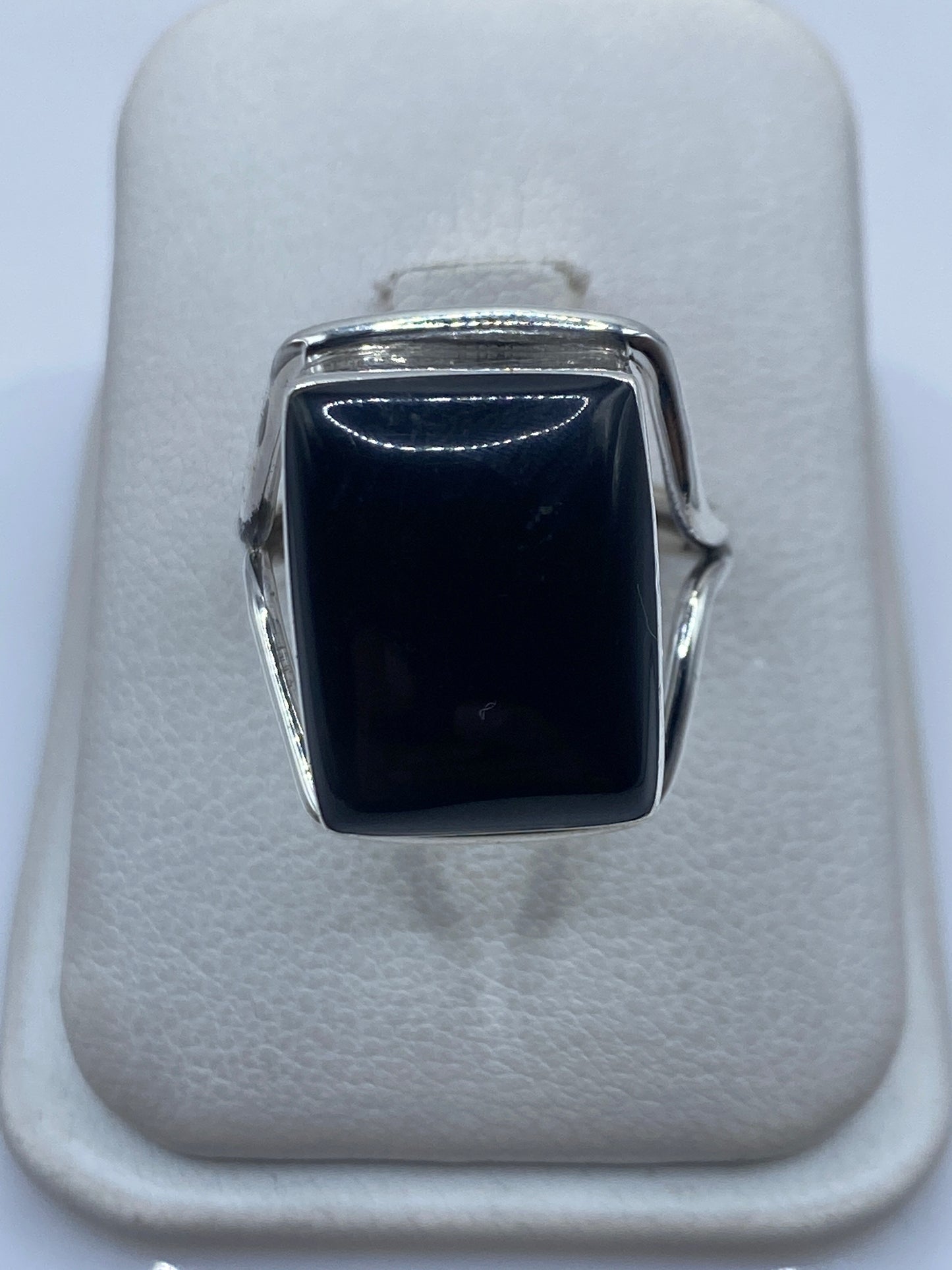 Anillo de plata con ónix negro cuadrado en vitrina blanca, vista frontal