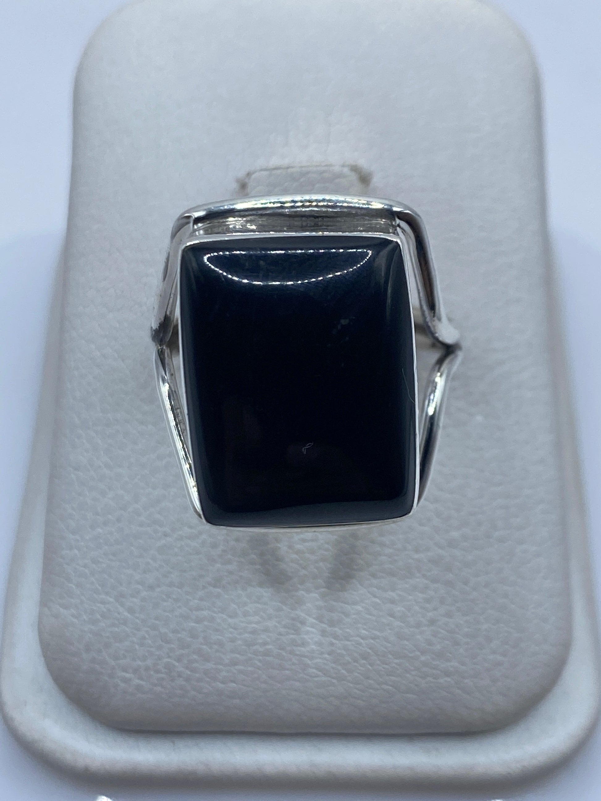 Anillo de plata con ónix negro cuadrado en vitrina blanca, vista frontal