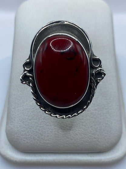 Anillo de plata ajustable con coral rojo engastado en la mano de una mujer