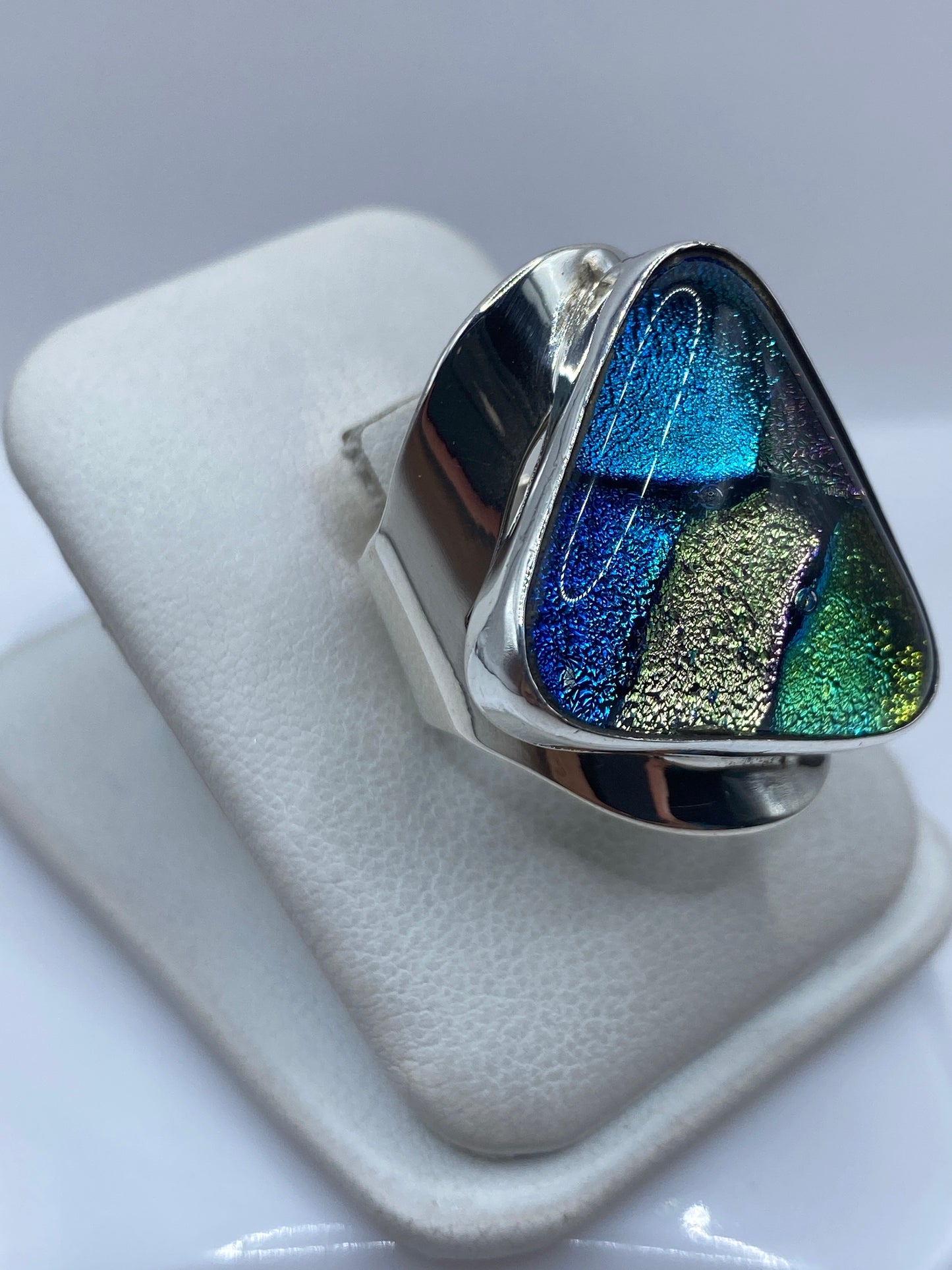 Vista frontal del anillo multicolor iridiscente mostrando los compartimentos de azul, verde y dorado
