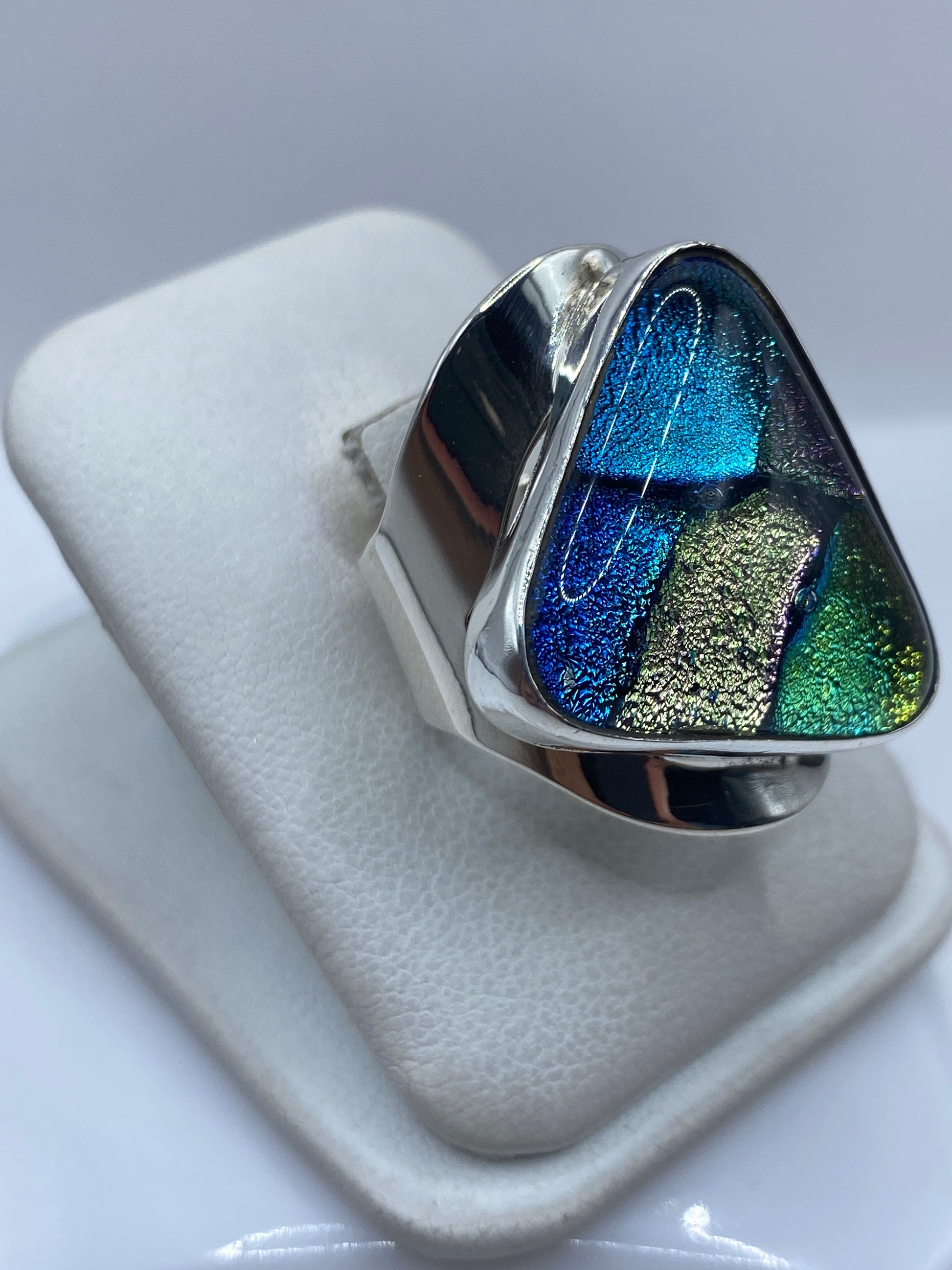 Vista frontal del anillo multicolor iridiscente mostrando los compartimentos de azul, verde y dorado