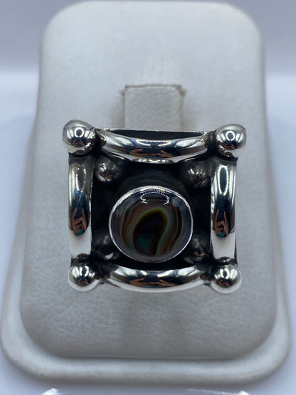 Anillo de plata solitario ajustable con piedra engastada, visto de frente sobre cojín blanco