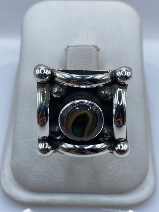 Anillo de plata solitario ajustable con piedra engastada, visto de frente sobre cojín blanco