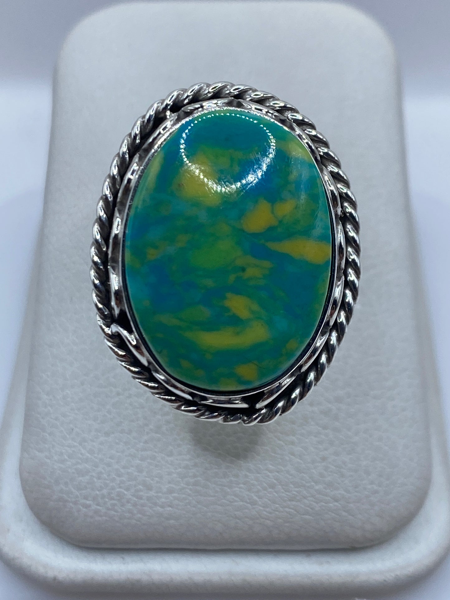 Anillo de plata ajustable con piedra verde sobre presentador blanco