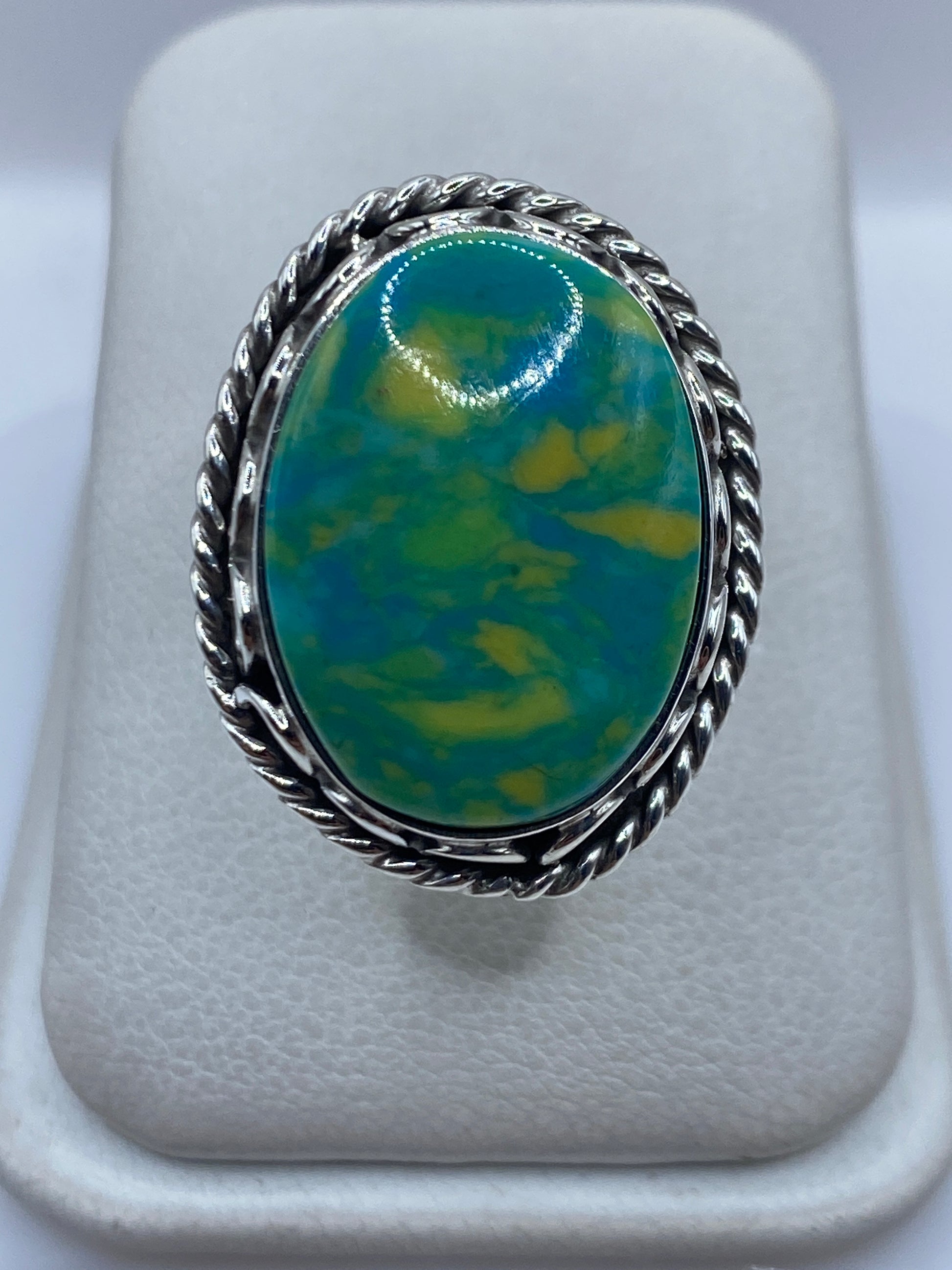 Anillo de plata ajustable con piedra verde sobre presentador blanco