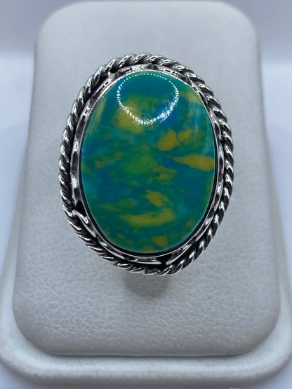 Anillo de plata ajustable con piedra verde sobre presentador blanco