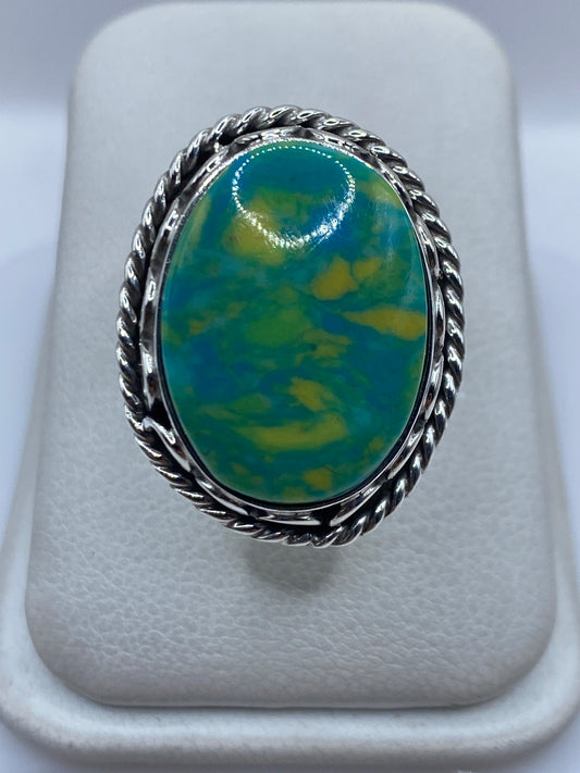 Anillo de plata ajustable con piedra verde sobre presentador blanco