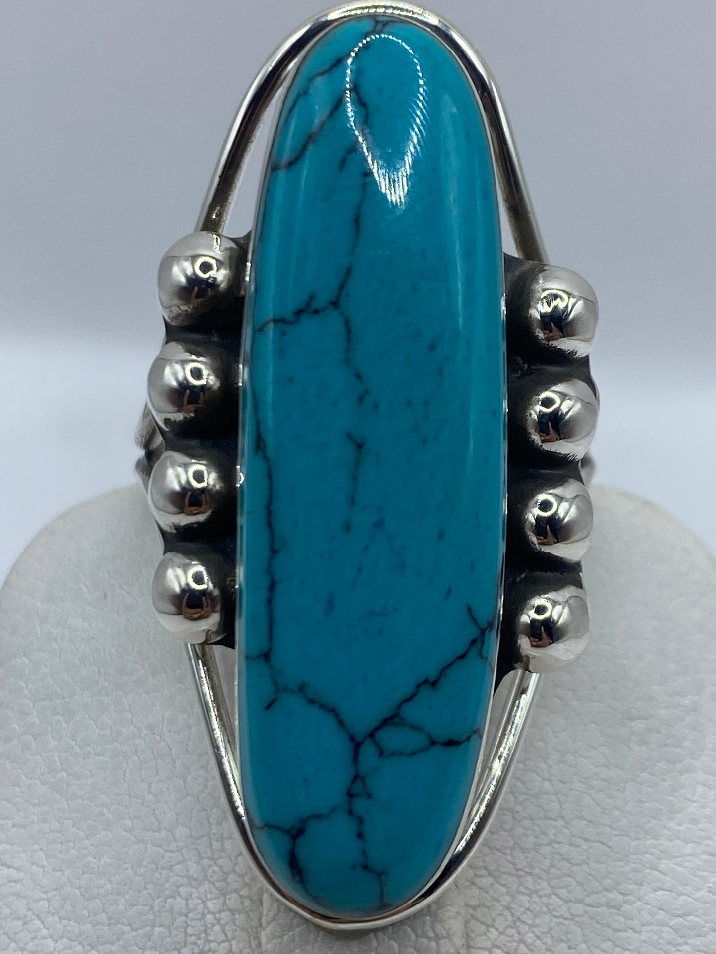 Anillo puesto en dedo de mujer, turquesa azul cielo brillante con vetas naturales