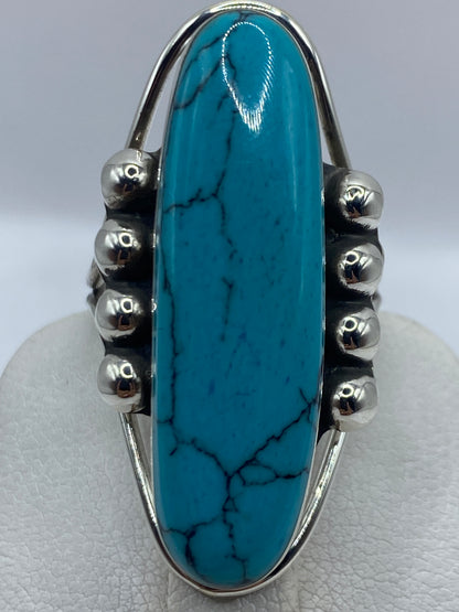 Anillo puesto en dedo de mujer, turquesa azul cielo brillante con vetas naturales