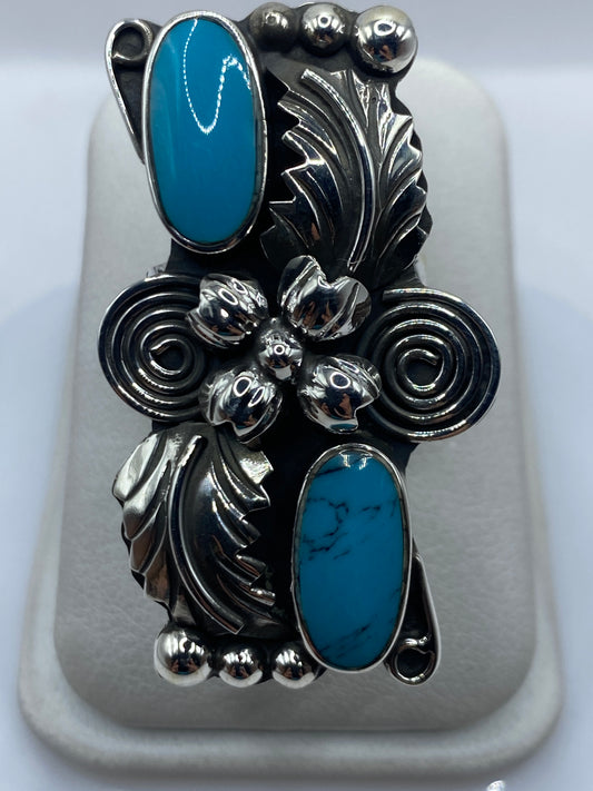 Anillo ajustable de plata con turquesa azul cielo y detalles repujados, visto de frente sobre fondo blanco