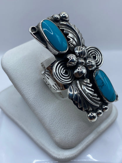 Detalle lateral del anillo mostrando el engaste de turquesa a mano y la textura repujada de la plata