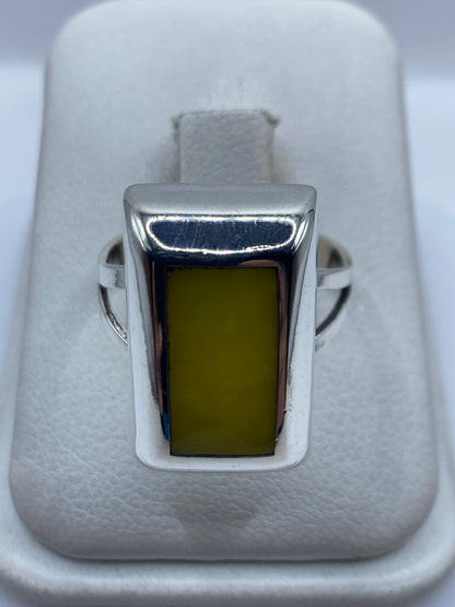 Anillo de plata cuadrado con piedra amarilla engastada, en estuche de terciopelo blanco