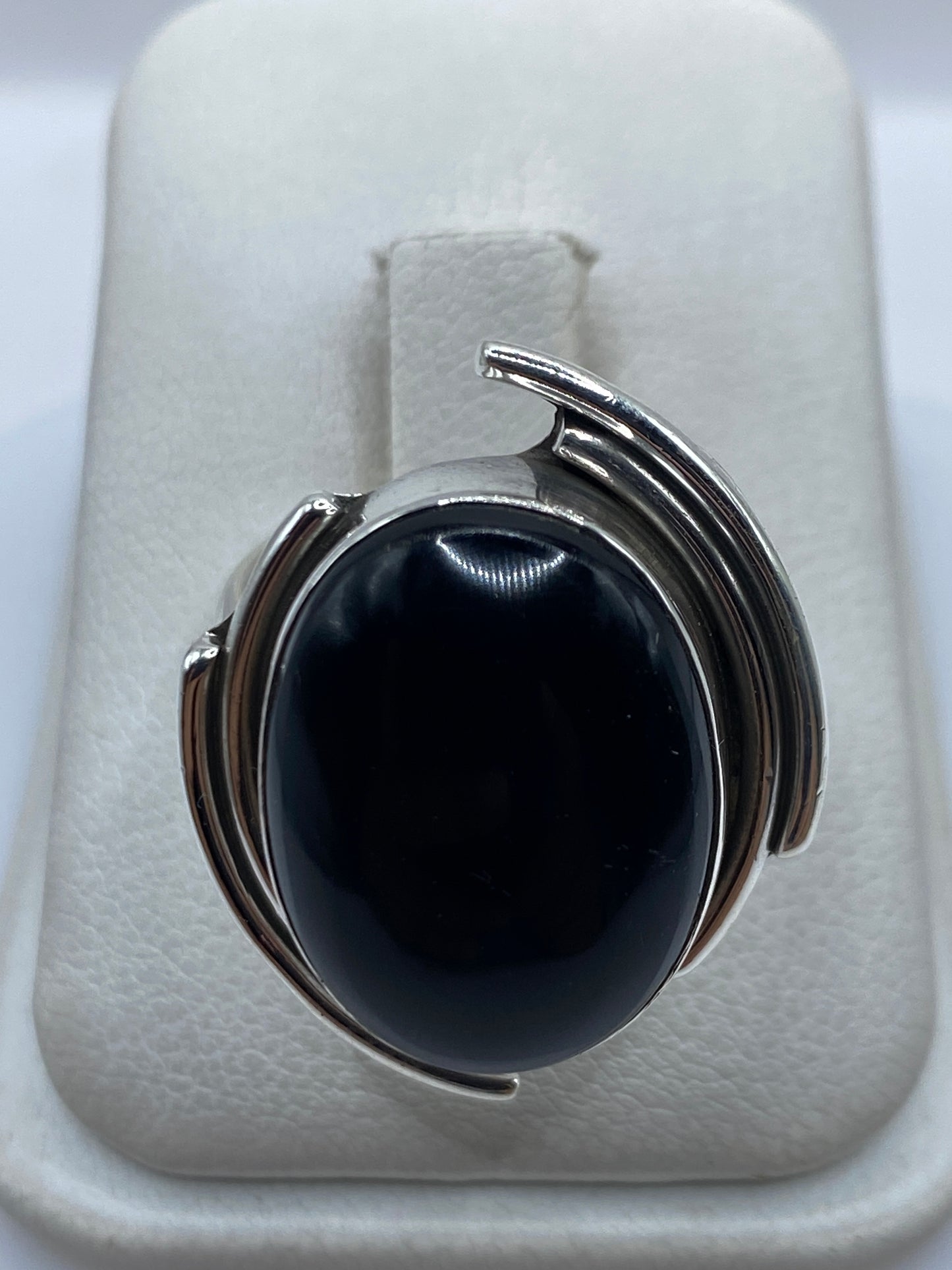 Anillo de plata con ónix negro engastado, vista frontal sobre presentador blanco