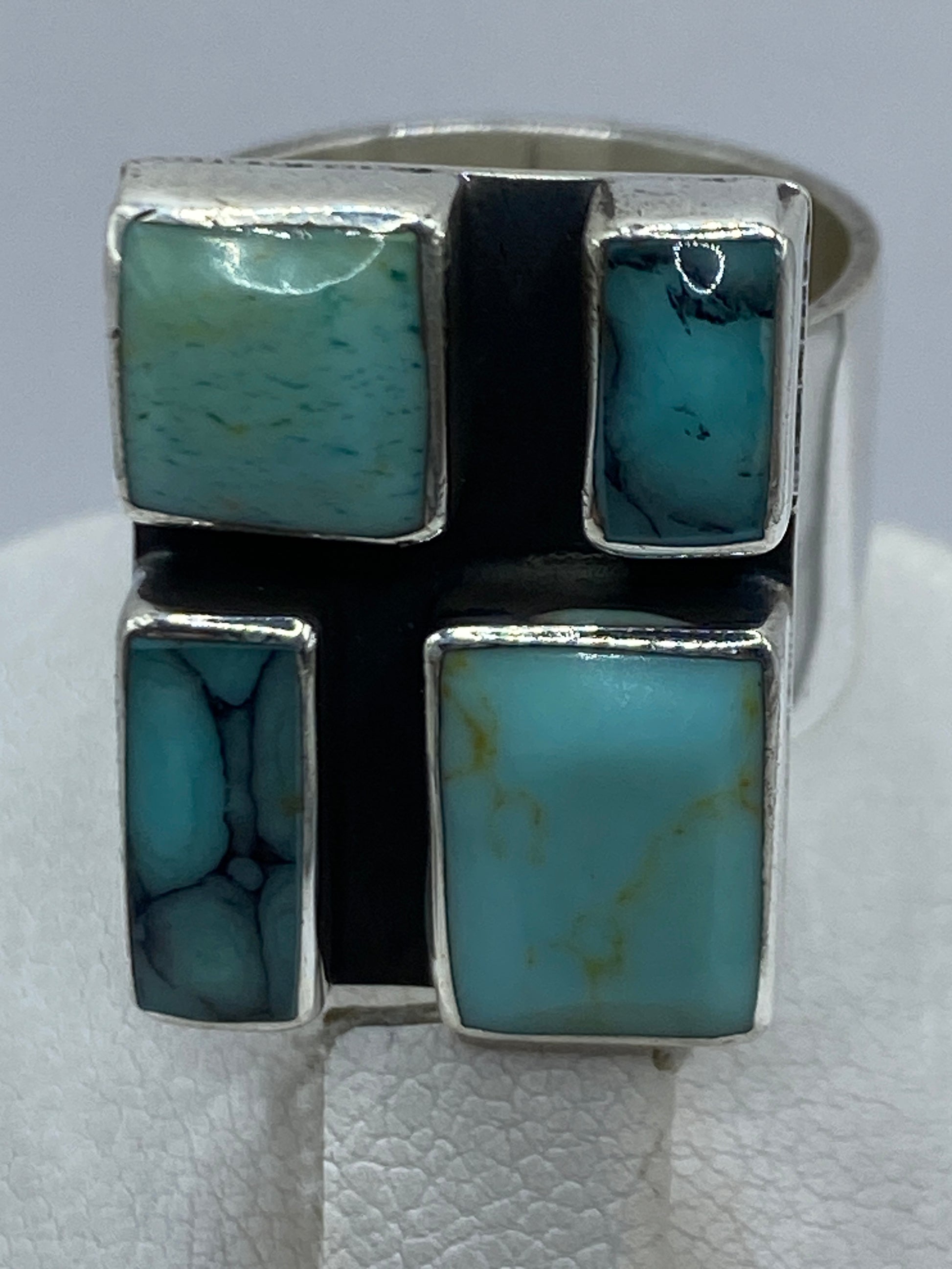 Detalle lateral del anillo mostrando el marco de plata y el engaste de turquesa a mano