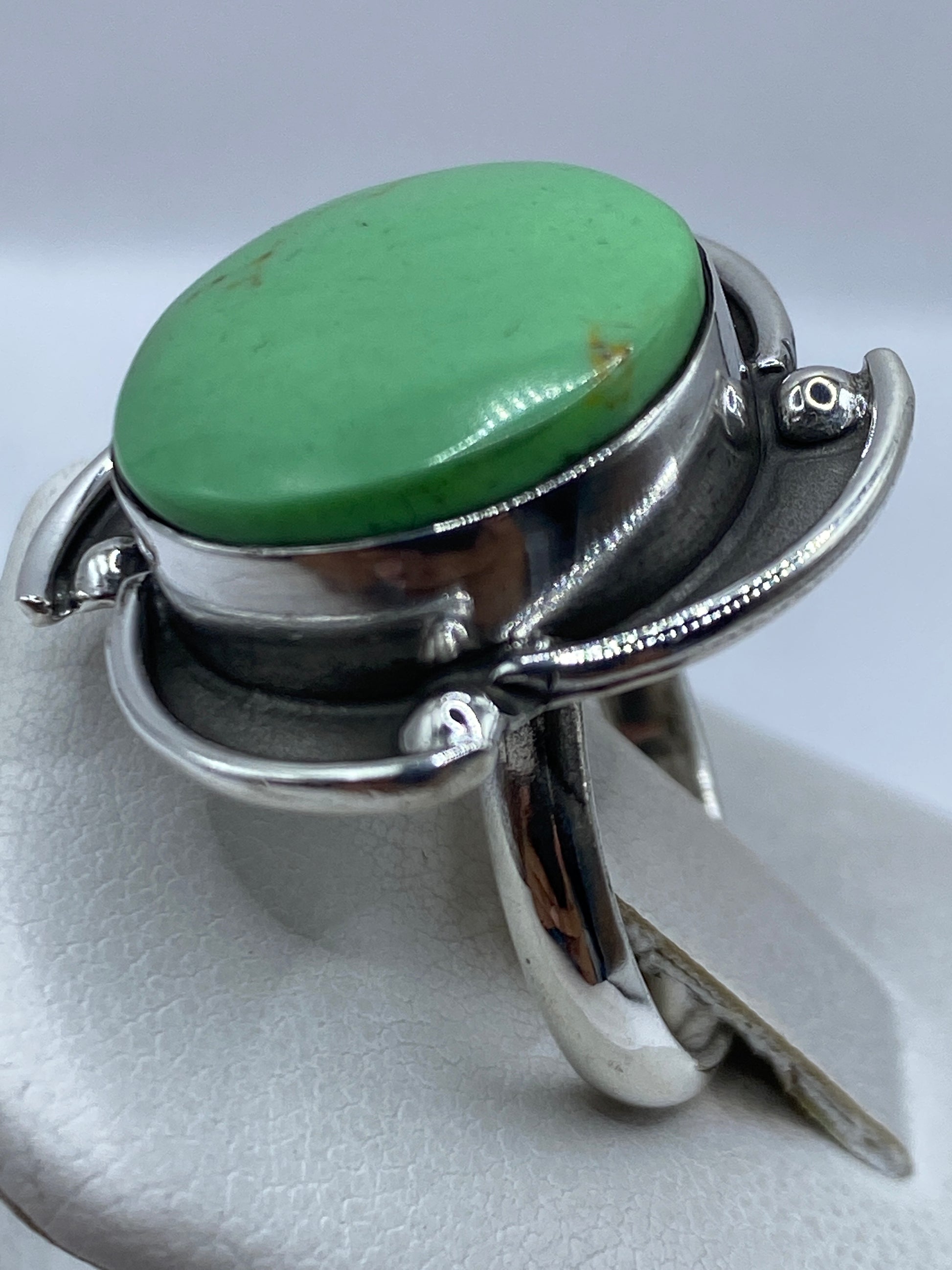 Anillo ajustable en la mano mostrando la piedra verde y el acabado de plata