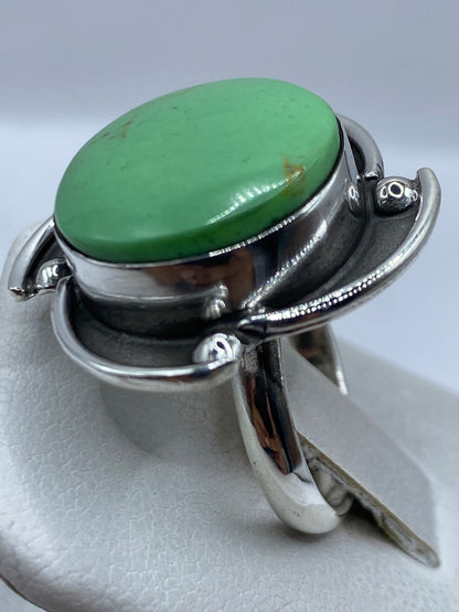 Anillo ajustable en la mano mostrando la piedra verde y el acabado de plata