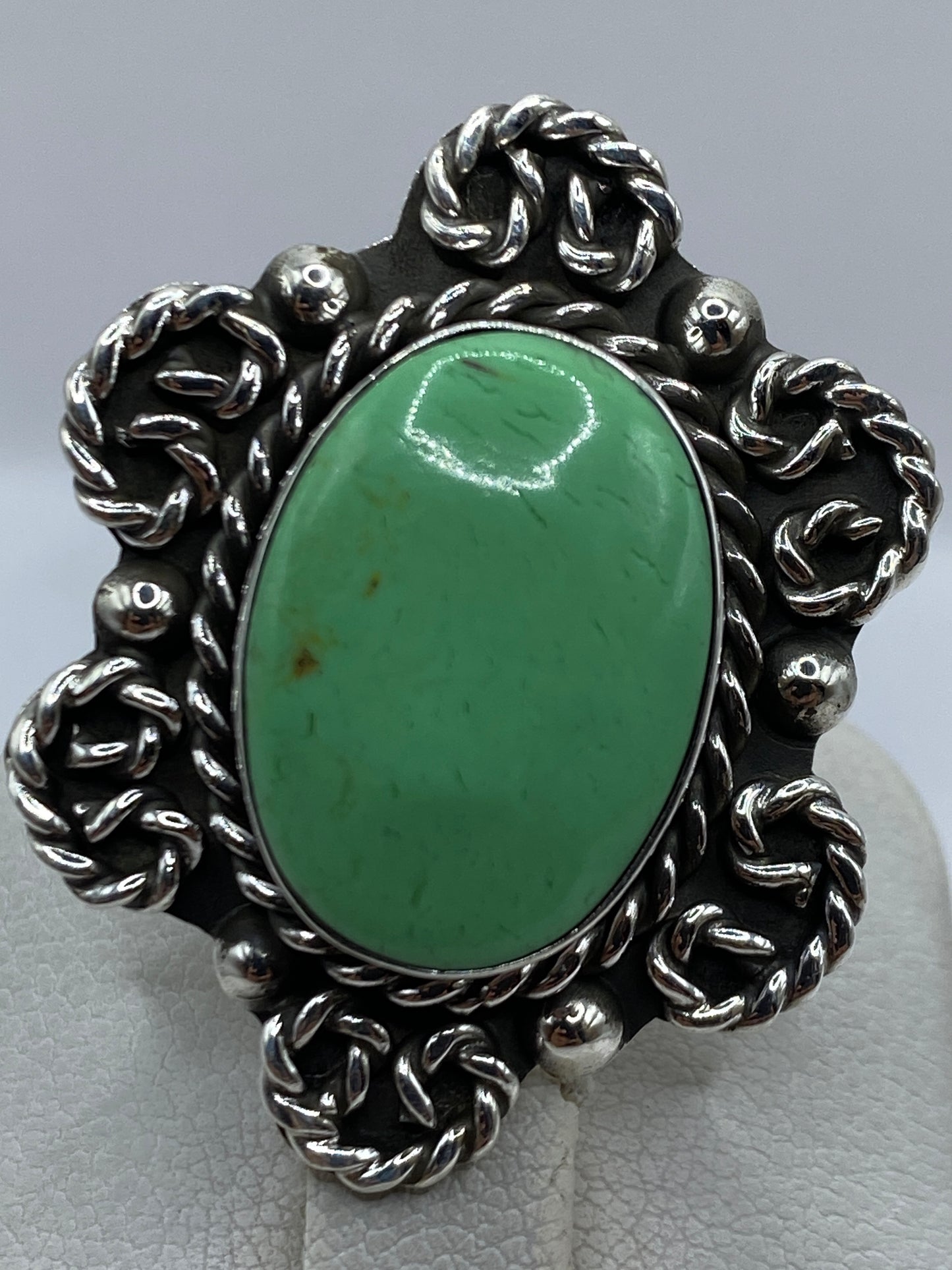 Anillo de plata verde en la mano, mostrando el tamaño y el trabajo del metal