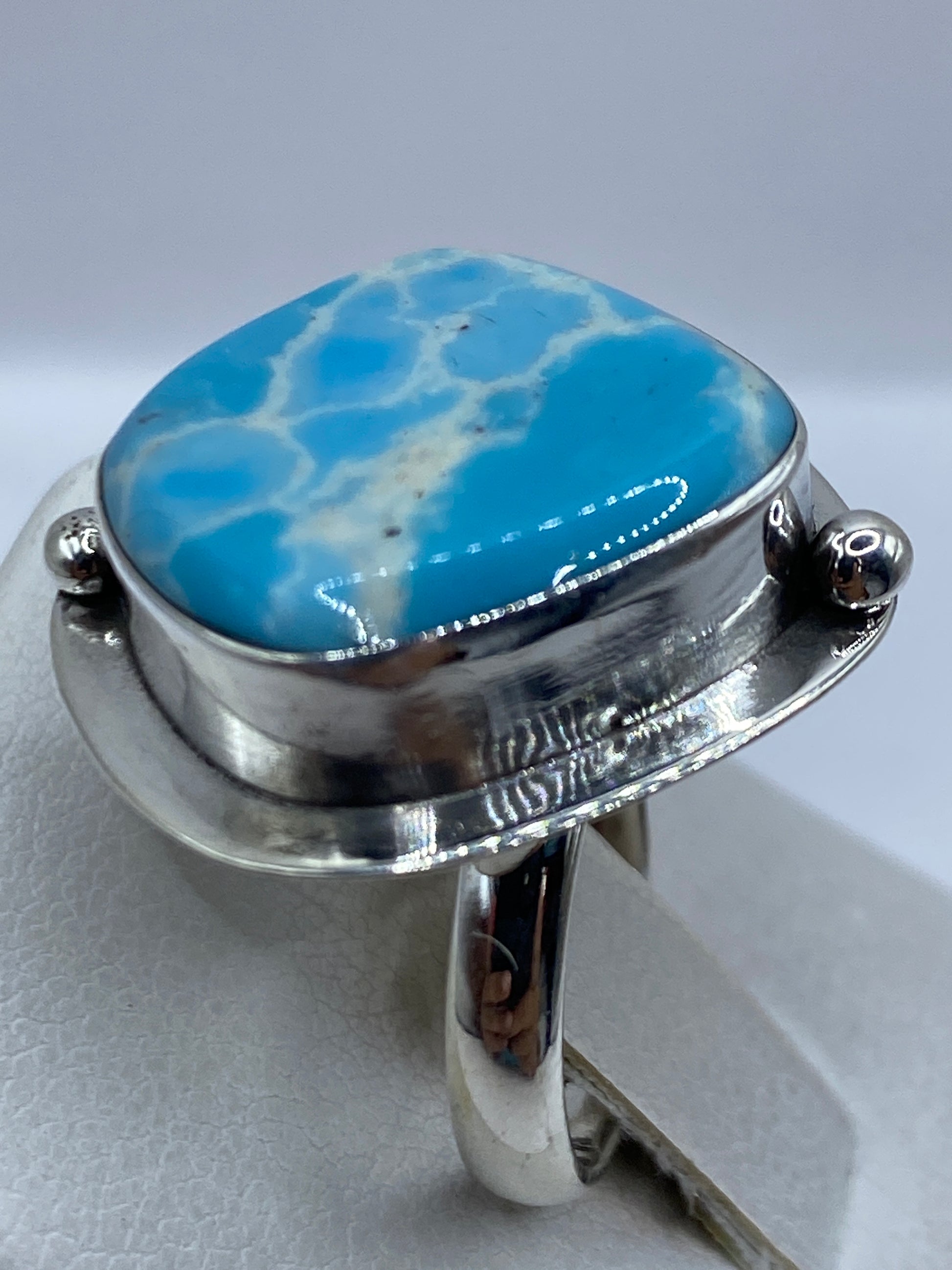Detalle del engaste a mano de la piedra azul en marco de plata